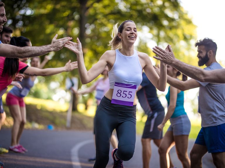 mujer acabando una media maratón, animada por el público