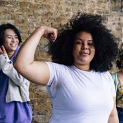 young woman flexing muscle with male and female friends in background