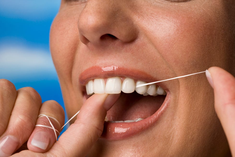 young woman flossing her teeth, closeup