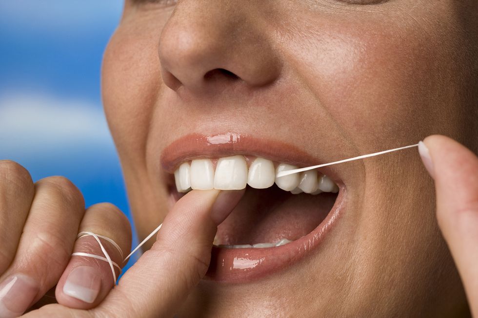 young woman flossing her teeth, closeup