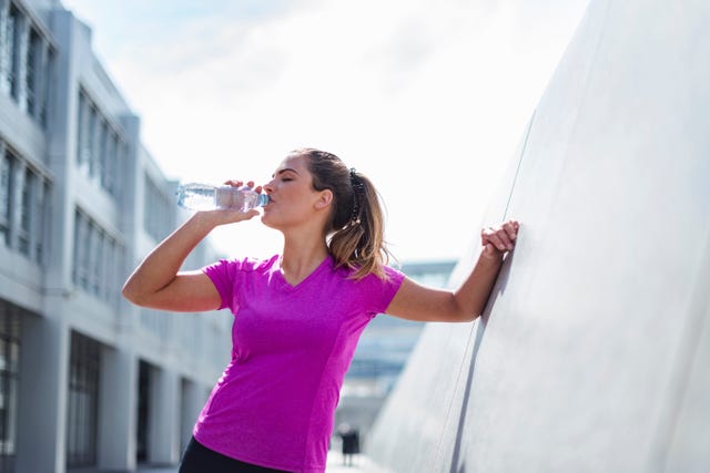 young woman having a break from exercising drinking from bottle