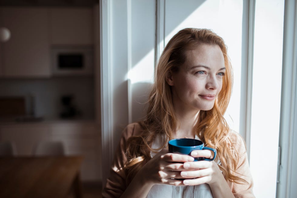 mujer tomando cafe y aprovechando la luz solar