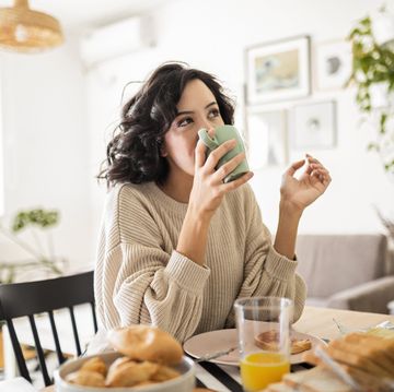 young woman having breakfast at home drinking coffee