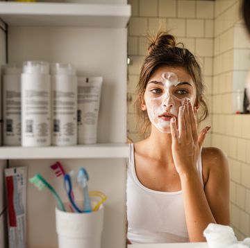 vrouw reinigt gezicht voor een badkamerspiegel