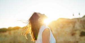 young woman head ups with eye closed against beautfiul sunset