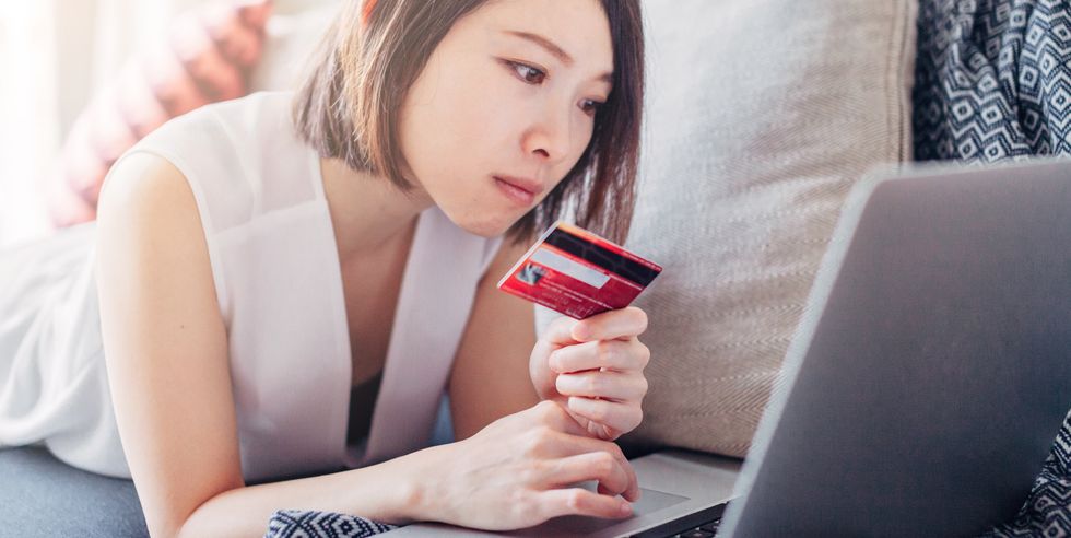 Young woman holding credit card and using laptop