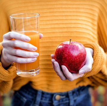young woman holding glass of apple juice and fresh apple