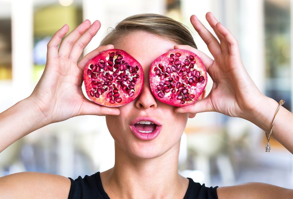 young woman holding pomegranate slices as glasses