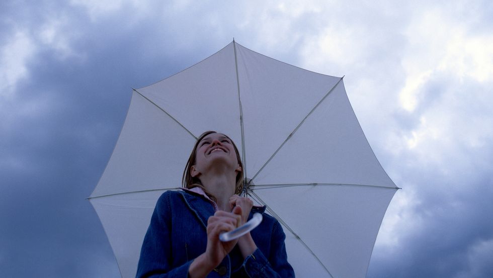 young woman holding umbrella, smiling, low angle view