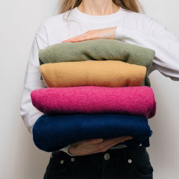 a woman holds four warm sweaters in her hands