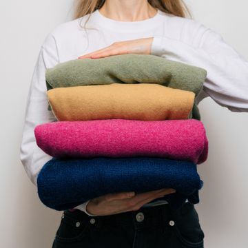 a woman holds four warm sweaters in her hands