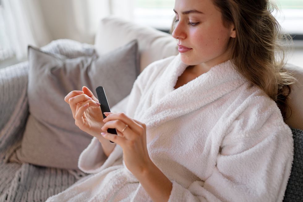 young woman in bathrobe taking care of her nails.