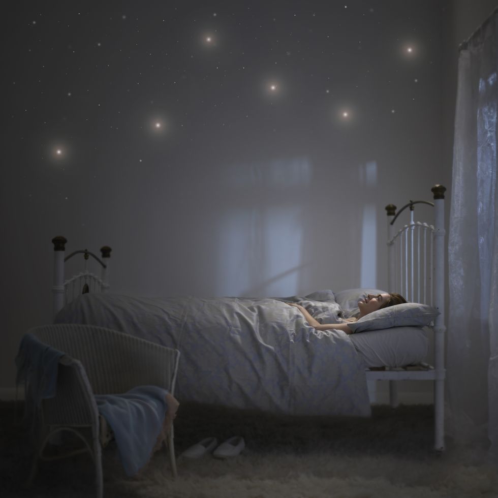 young woman in bed looking up at stars