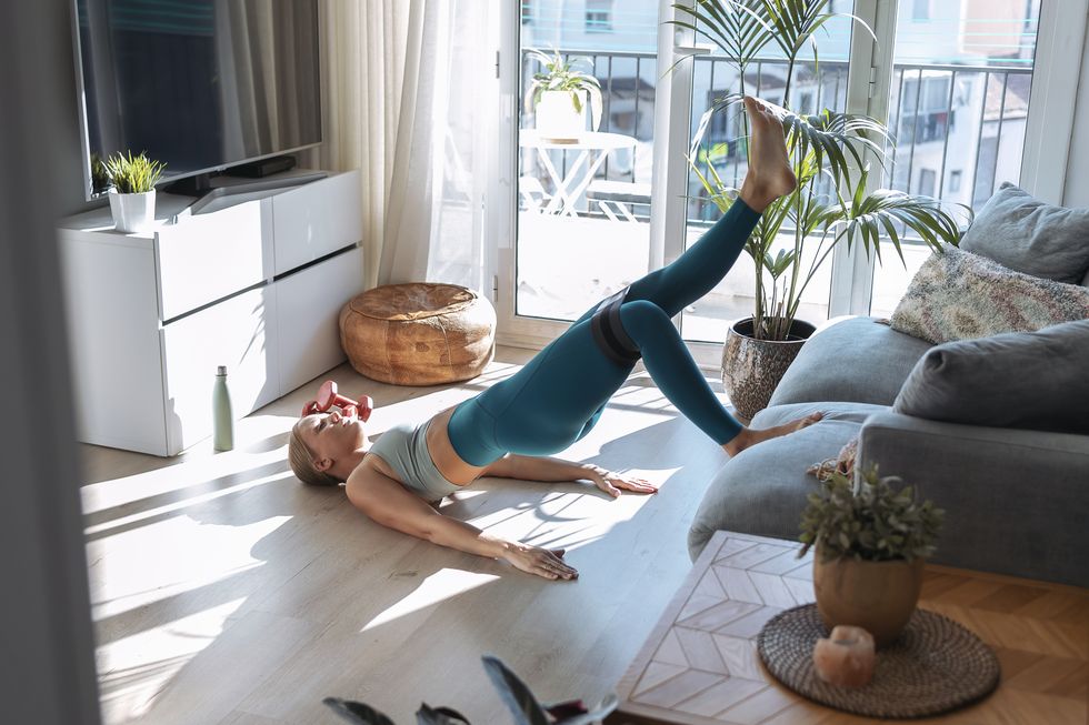 young woman in bridge position exercising while leaning on couch at home
