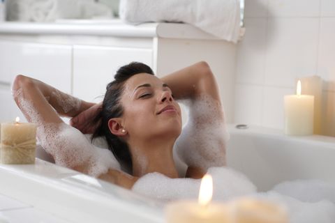 Young woman in bubble bath, smiling