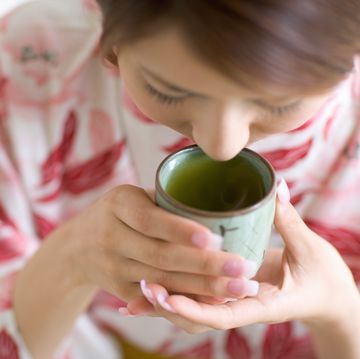 young woman in kimono drinking form cup, close up