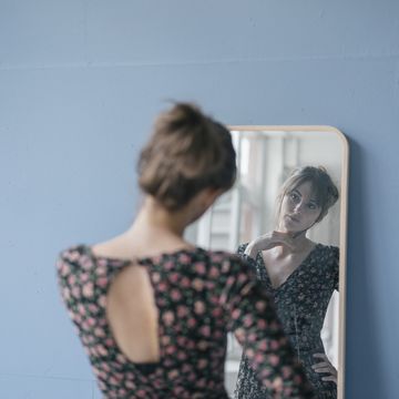 young woman in vintage dress looking into mirror