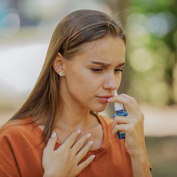 young woman is having sinusitis problems outside in nature