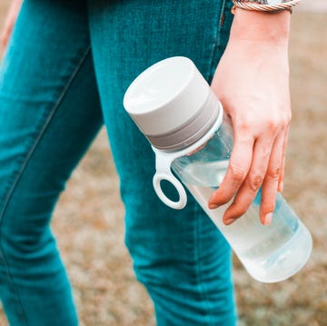 A young woman is holding a reusable water bottle container outdoors