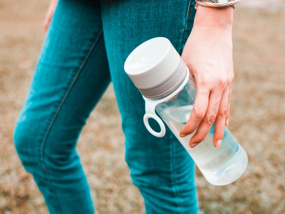 https://hips.hearstapps.com/hmg-prod/images/young-woman-is-holding-a-reusable-water-bottle-royalty-free-image-1703186804.jpg?crop=0.88557xw:1xh;center,top&resize=1200:*