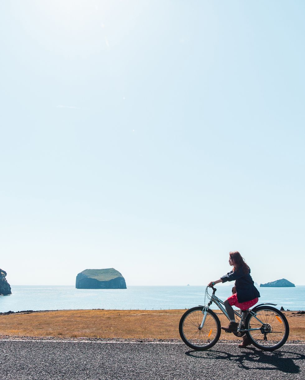 a young woman is riding bicycle by the shore