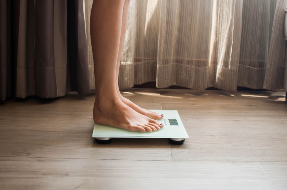 a young woman is weighing herself in a weighing scale