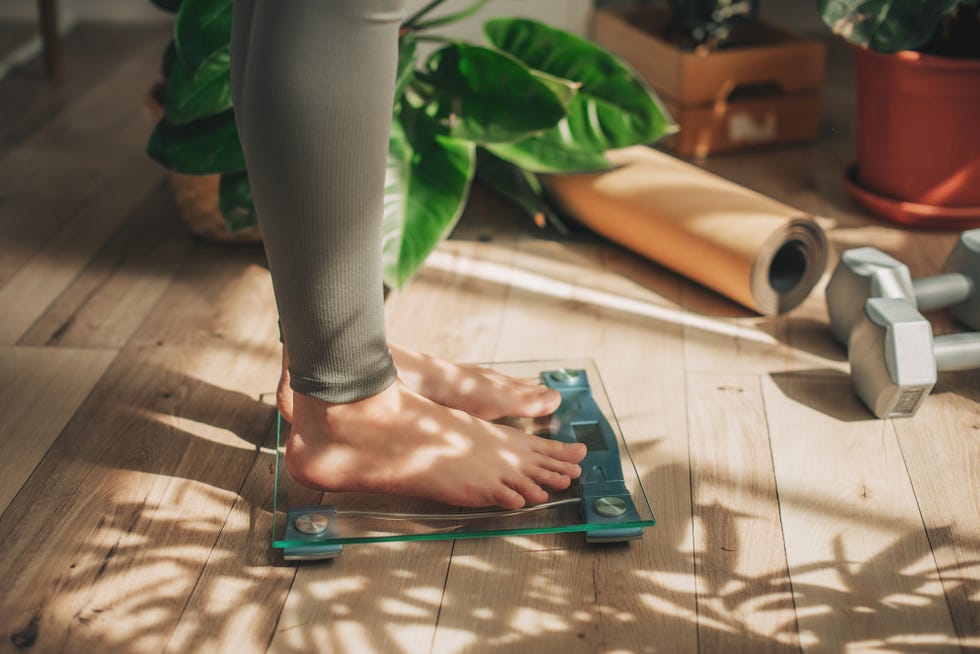 a young woman is weighing herself in a weighing scale