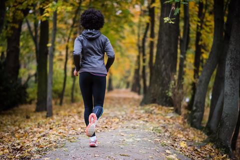 young woman jogging through the fall park, rear shot