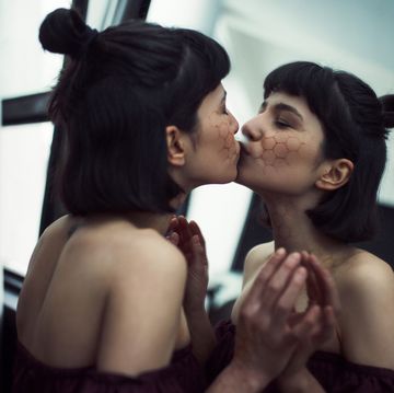 young woman kissing her reflection