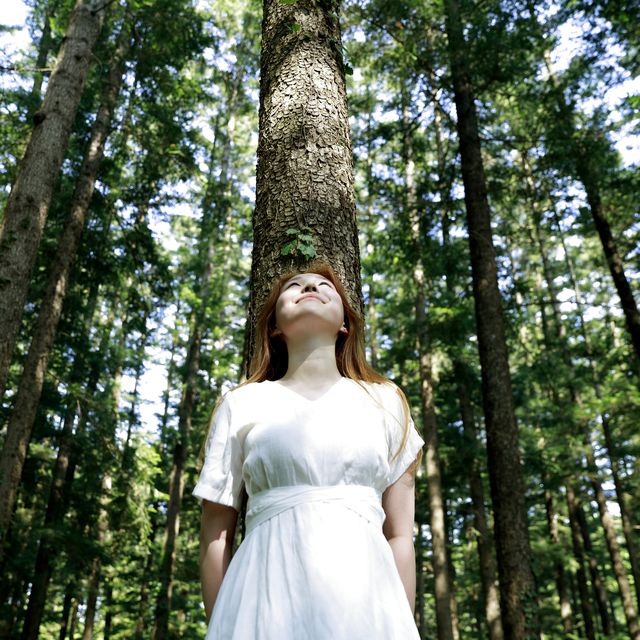 young woman leaning against tree in forest