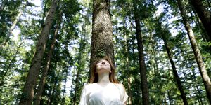 young woman leaning against tree in forest