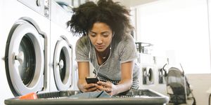 young woman listening to headphones in laundromat