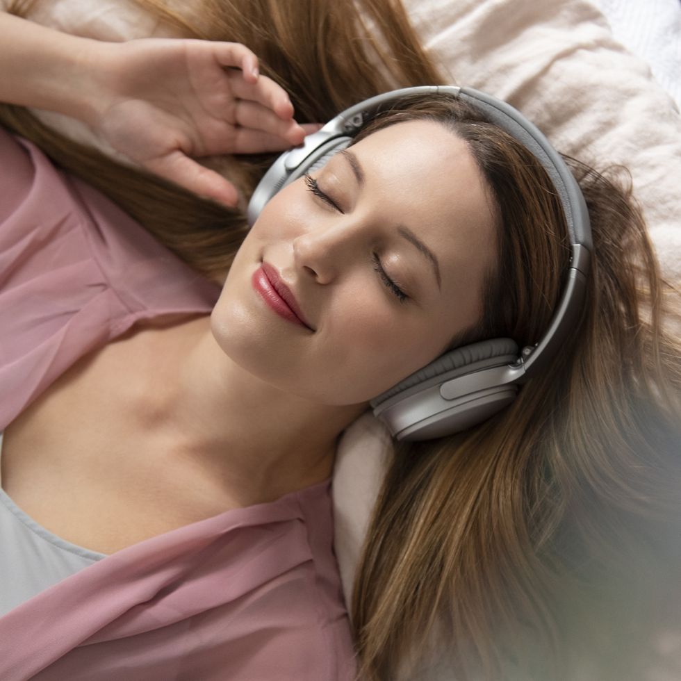 young woman listening to music on bed