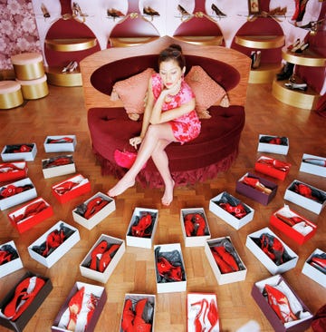 Young woman looking at boxes of red shoes on shop floor, elevated view