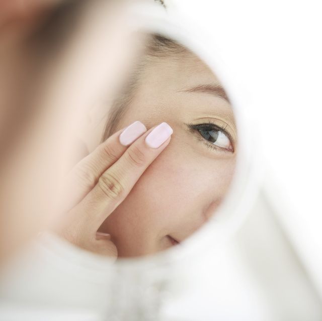 how to care for eye skin, young woman looking at self in mirror skin care