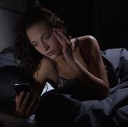 Young woman looking at smartphone in bed