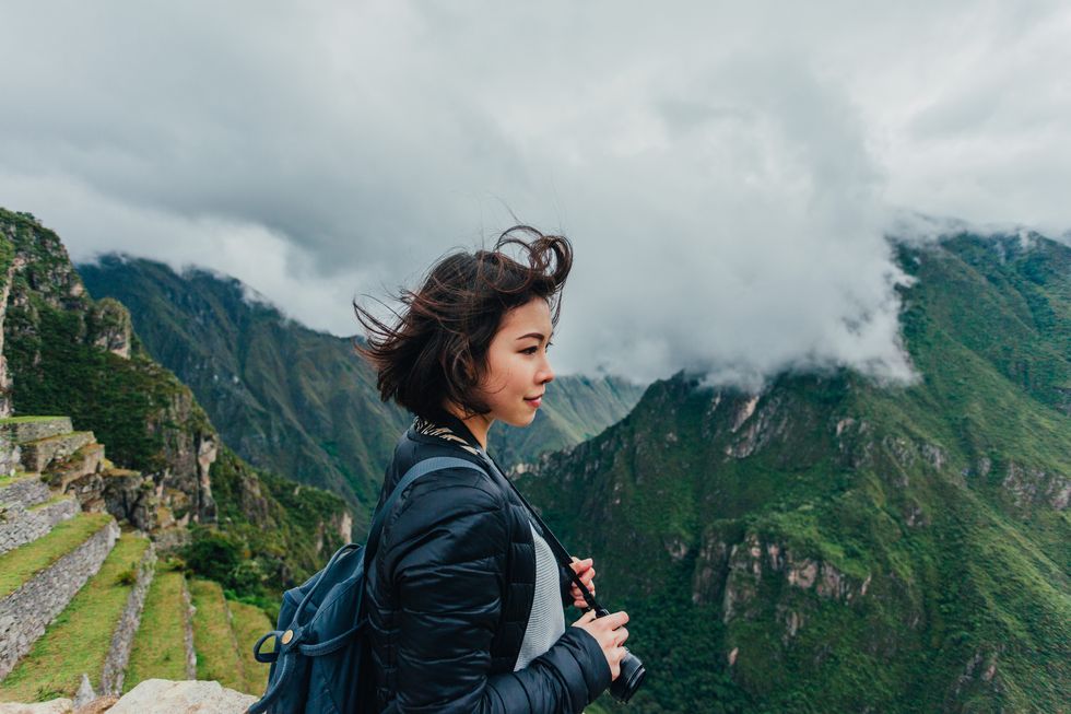 young woman looking at view from machu picchu in peru