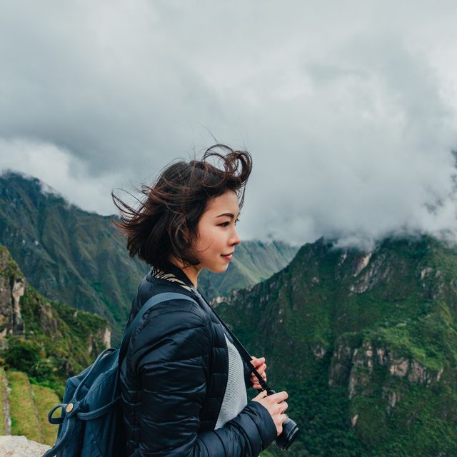 young woman looking at view from machu picchu in peru
