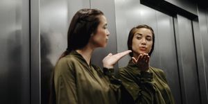 Young woman looking in mirror in elevator blowing a kiss