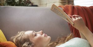 young woman lying on sofa reading