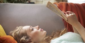 young woman lying on sofa reading