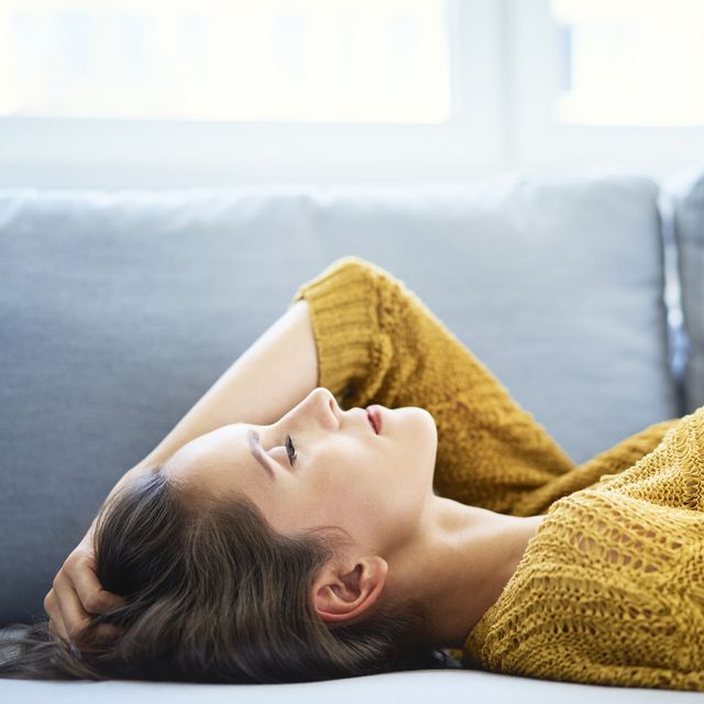 mild v severe covid symptoms  young woman lying on sofa with eyes closed and relaxing