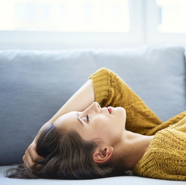 young woman lying on sofa with eyes closed and relaxing