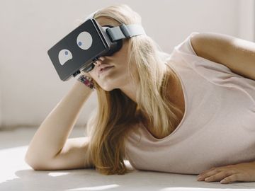 Young woman lying on the floor wearing VR glasses with squinting eyes