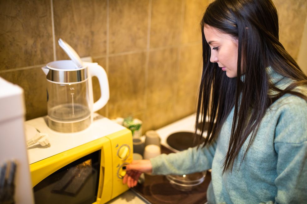 a young woman making microwave popcorn