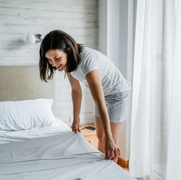 young woman making the bed in the morning
