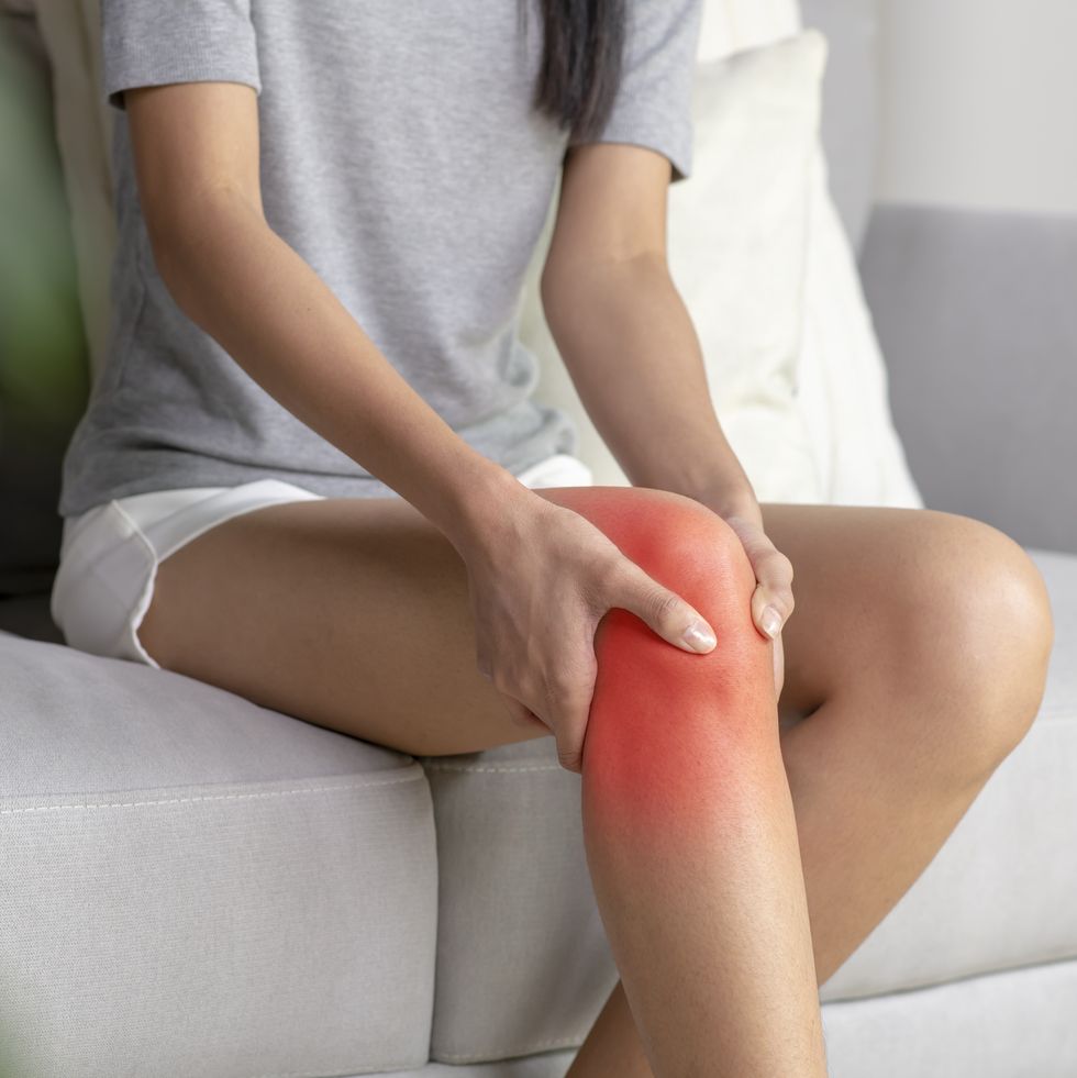 a young woman massaging her painful knee marked with red spot