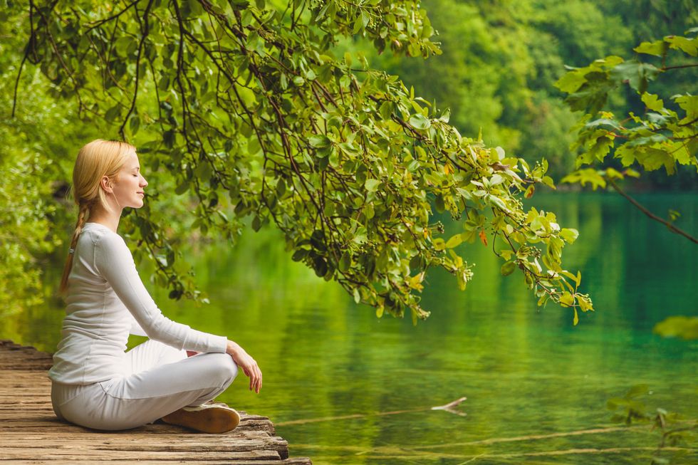 Young woman meditating by the water.