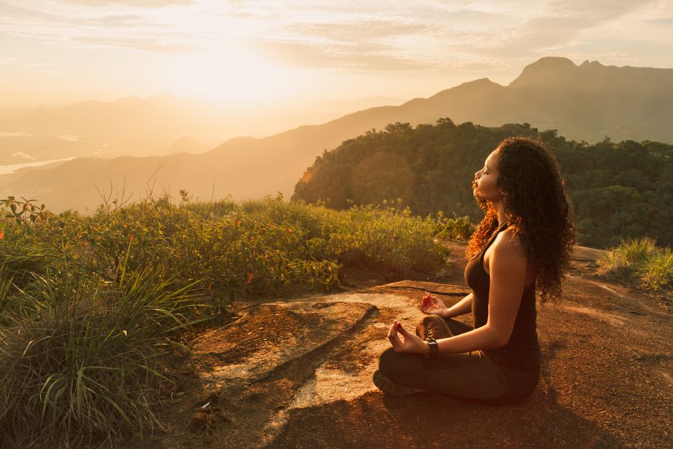 young woman meditating on mountain top