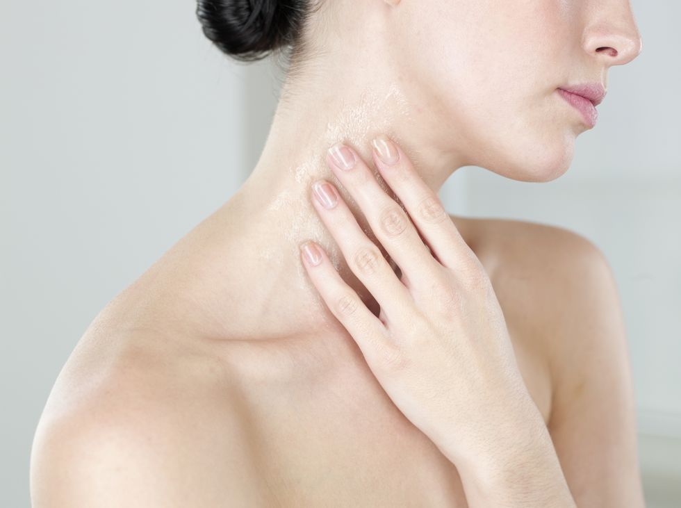 Young woman moisturizing neck